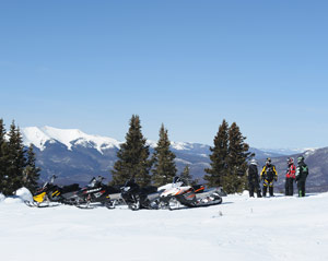 Beautiful snowmobiling scene of a group of snowmobilers and a mountain vista